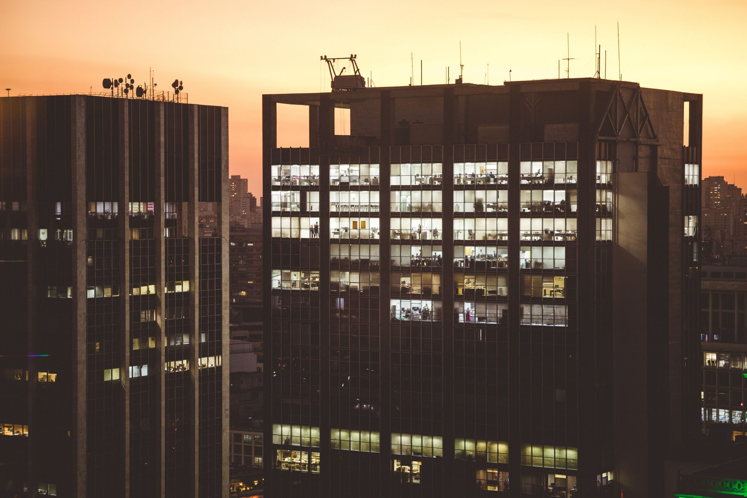 City office buildings illuminated against a sunset backdrop, showcasing urban life.